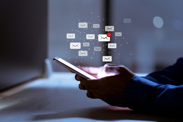 Close up of someone holding a phone. The screen is lit up and there are illustrated email icons coming out of the screen. Blog: MailerLite: The best email marketing platform for small businesses?