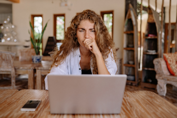 Image of a woman at her dining room table, deep in thought looking at her laptop. Blog: Is an email list worth it for a small business?