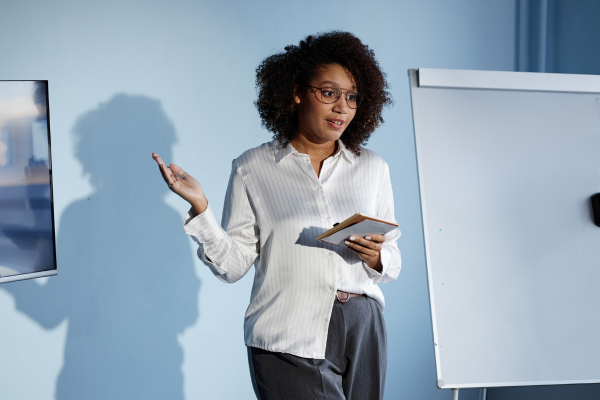 Woman standing at the front of the room giving a talk / presentation. Blog: Why you don’t need to be a tech expert to nail email marketing