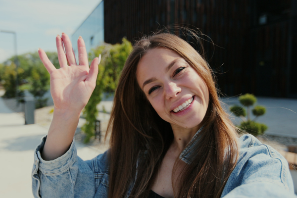 Woman smiling and waving looking open and welcoming.Blog: What happens after someone signs up